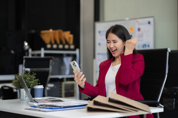 Businessman using smartphone and laptop computer in office. Happy woman, entrepreneur, small business owner working online.