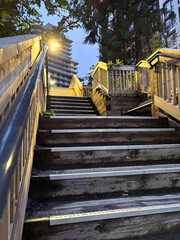 Wooden staircase with illuminated handrails leading to urban apartments