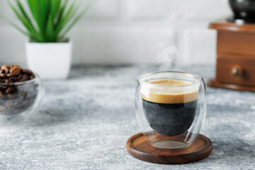 espresso in glass cup on table on white brick wall background