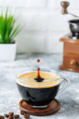 espresso with drop in glass cup on table on white brick wall background