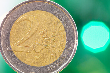 Face of 2 euro coin with blurred green bouquet in the background.