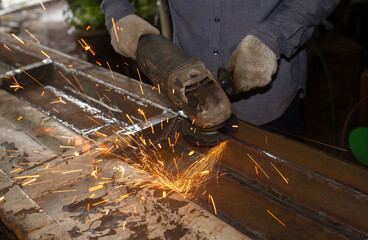 Heavy Industry Engineering Factory Interior with Industrial Worker Using Angle Grinder and Cutting a Metal Tube.