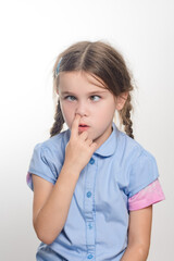 A closeup shot of a girl with pigtails, wearing a light blue shirt, playfully touching her nose with a mischievous expression. The background is plain white.