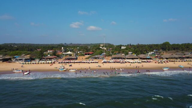 Aerial drone shot of shacks and crwoded enjoying at baga beach in goa
