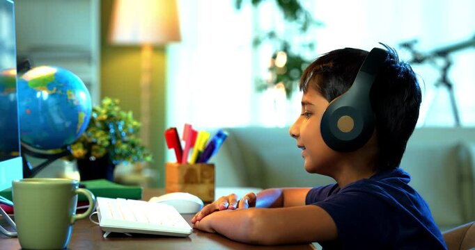 Studious Indian Asian Boy Attending Online Class at Home Using Computer, Learning Virtually and Communicating with Teacher, Highlighting Modern Education, E-Learning, and Technology in Daily Life