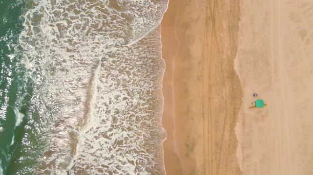 Aerial top down drone shot of ocean tides, big ocean tides at beach