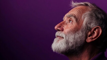 Obraz premium A man with a beard and gray hair is looking up at something