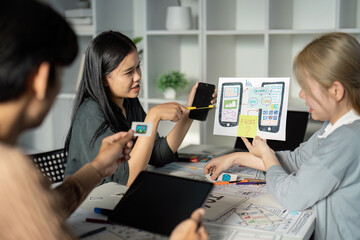 Creative UX UI Design Team Brainstorming Session with Digital Devices and Wireframes in Modern Office Environment