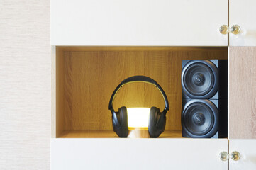 Modern audio equipment showcased on wooden shelf with glowing light and speakers. Wireless...