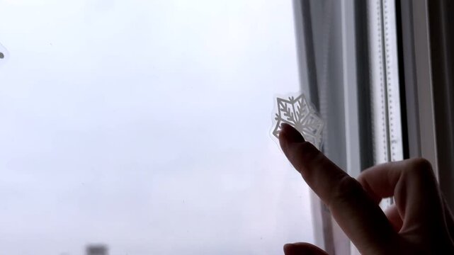 A woman applies snowflake stickers to a window