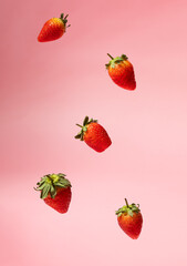 Floating ripe strawberries against a soft pink background, creating a dynamic and vibrant food photography composition. Perfect for healthy eating, summer vibes, and organic produce concepts.