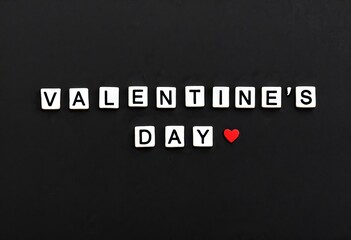 The words "VALENTINE'S DAY" spelled out in white blocks on a black textured background with a single red heart. Perfect for Valentine's Day projects, it evokes a sense of modern romance.