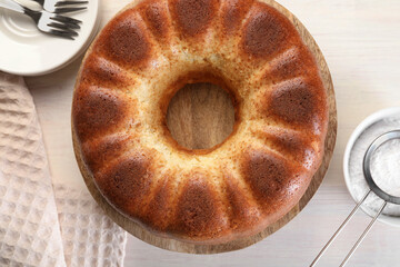 Freshly baked sponge cake served on white wooden table, top view