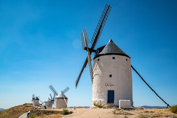 Fototapeta premium Iconic Consuegra Windmills Against a Clear Blue Sky, Spain