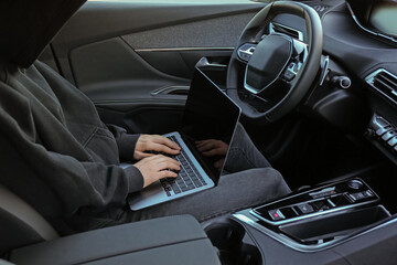 Thief hacking car system with laptop inside vehicle, closeup