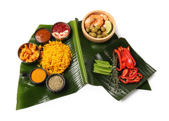 Piece of banana leaf with different food, spices and sauce isolated on white, top view. Healthy eco...