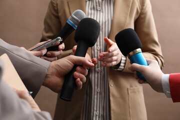 Group of journalists interviewing businesswoman on beige background, closeup