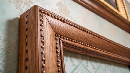Obraz premium A focus on the delicate detailing of wooden pegs securing the frame with the rich color of the exposed joinery contrasting against the backdrop of a soft muted wall finish. The