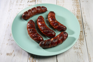 Sausages on a blue plate on a wooden board