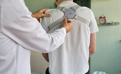 Doctor fits a back brace to a child in a clinic to support the spine and for rehabilitation