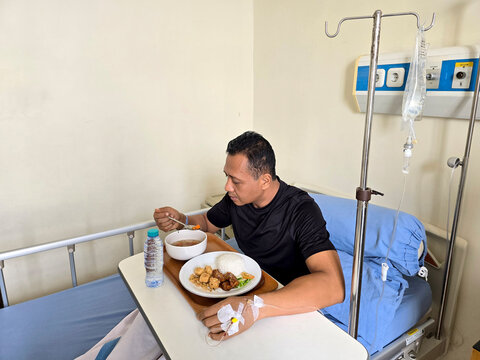 Medical Recovery &ndash; Patient Eating in Hospital Bed with IV