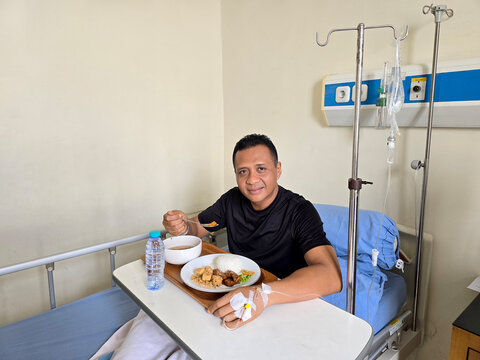 Patient enjoying hospital food, 40 year old male patient who was installed on an IV drips eating hospital food.