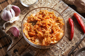 Fermented kim chi in a bowl with chilli peppers, sesame seeds, garlic and ginger