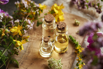 Bottles of aromatherapy essential oil with colorful summer flowers on a wooden table