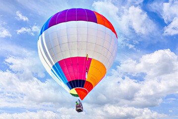 Naklejka premium Colorful hot air balloon flying over blue sky with white clouds 