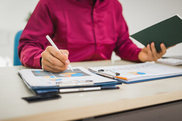 A focused man works diligently in his office, reviewing numerous accounting documents on his desk....