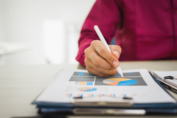 A focused man works diligently in his office, reviewing numerous accounting documents on his desk....