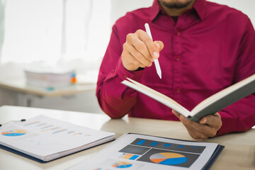 A focused man works diligently in his office, reviewing numerous accounting documents on his desk. His goal is to ensure accuracy and precision, avoiding errors in critical financial data.