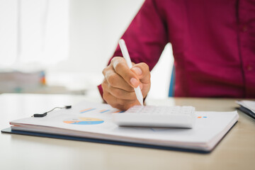 A focused man works diligently in his office, reviewing numerous accounting documents on his desk. His goal is to ensure accuracy and precision, avoiding errors in critical financial data.