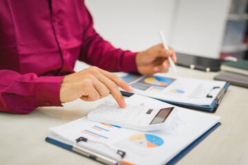 A focused man works diligently in his office, reviewing numerous accounting documents on his desk. His goal is to ensure accuracy and precision, avoiding errors in critical financial data.