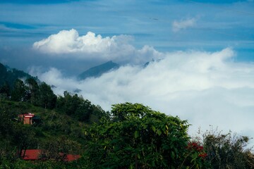 Scenic mountain view with clouds and red-roofed house.