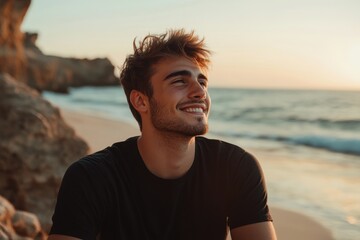Young Man Smiling on Beach at Sunset with Ocean Waves in Background