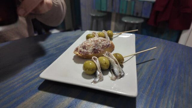 close-up view of traditional Spainsh tapas in a bar shared by two friend chatting and drinking homemade vermouth. 4K