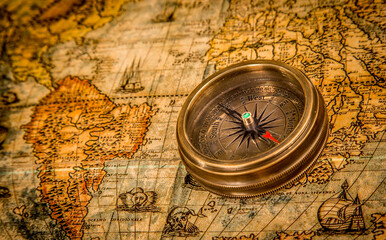 Vintage still life. Vintage compass lies on an ancient world map of 1565. Vintage style travel and adventure.