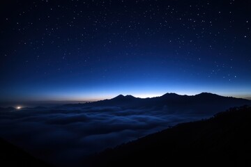 Naklejka premium A mountain range is silhouetted against a dark sky with a few stars