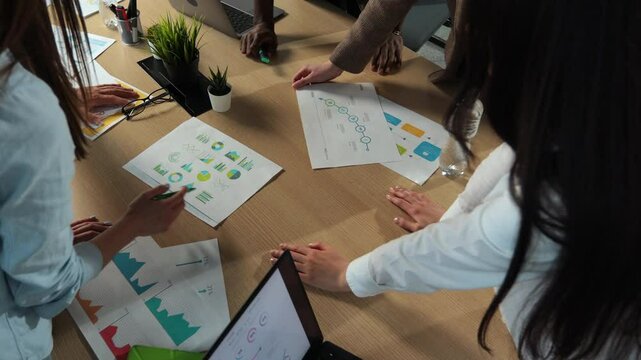 Top view Mixed race group of people office small business start up company planning creative meeting using digital tablets showing financial data and graphs.
