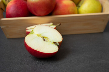 Fresh small organic red apples in a wooden crate on grey table background