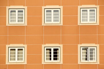 Symmetrical facade of an orange building with six white-framed windows.