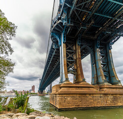 Fototapeta premium A view from the shore of the East river underneath the Manhattan bridge in New York, in the fall