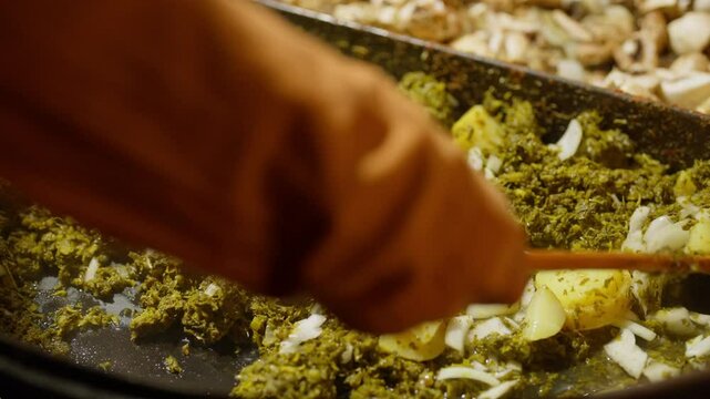 Slow Motion of cooking and making kale next to cham in a very big pan with onions and potatos. Making kale with potatoes and onions in a very big pan