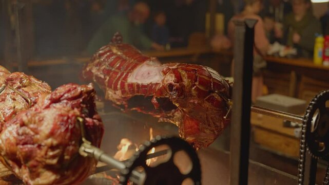 Roasted a whole big pig on fire. Grilled on a big skewer. Roasting piglet on a spit turns slowly roasting it. Barbecue. Street food. 4k. Lechon or Suckling popular dish. pigs roasting on fire pit and 