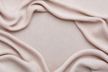 Fototapeta premium Close-up of delicate beige fabric with gentle folds, showcasing a soft and cozy texture. Ideal for themes of comfort, fashion, or interior design inspiration. 