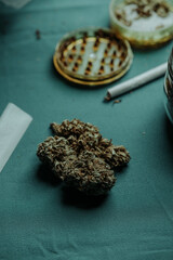 cannabis bud, spliff and grinder on a table