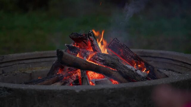 Warm wood crackling fireplace with glowing flames in slow motion - tranquil outdoor dark evening