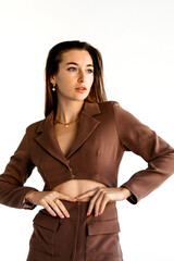 Young woman poses confidently in stylish brown blazer and trousers against a light background