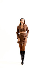 Model poses confidently in stylish brown outfit against plain white background during fashion shoot...